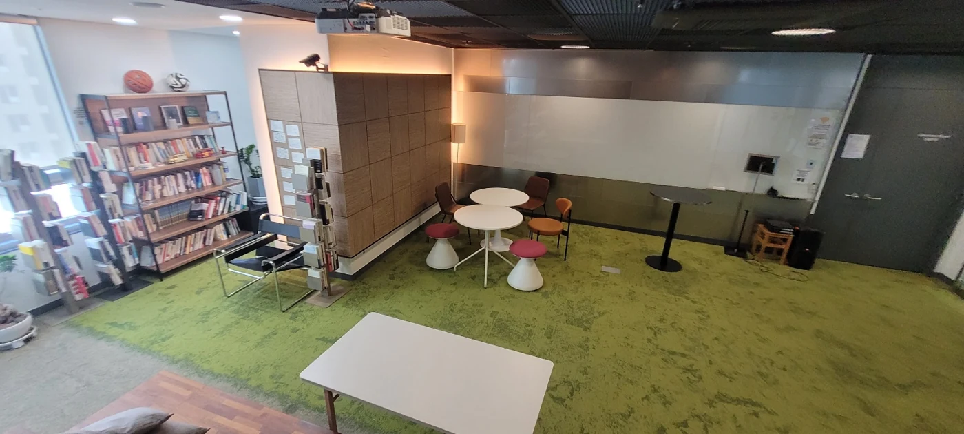 초록색 바닥과 원형 테이블, 화이트보드가 있는 코칭타운 서울 본원 Hall
